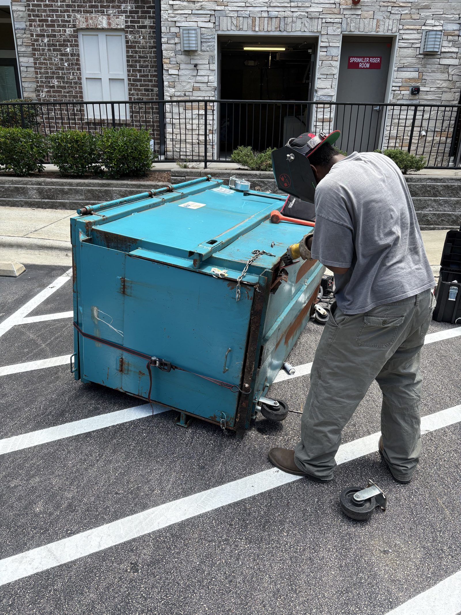 Technician repairing multifamily property waste equipment