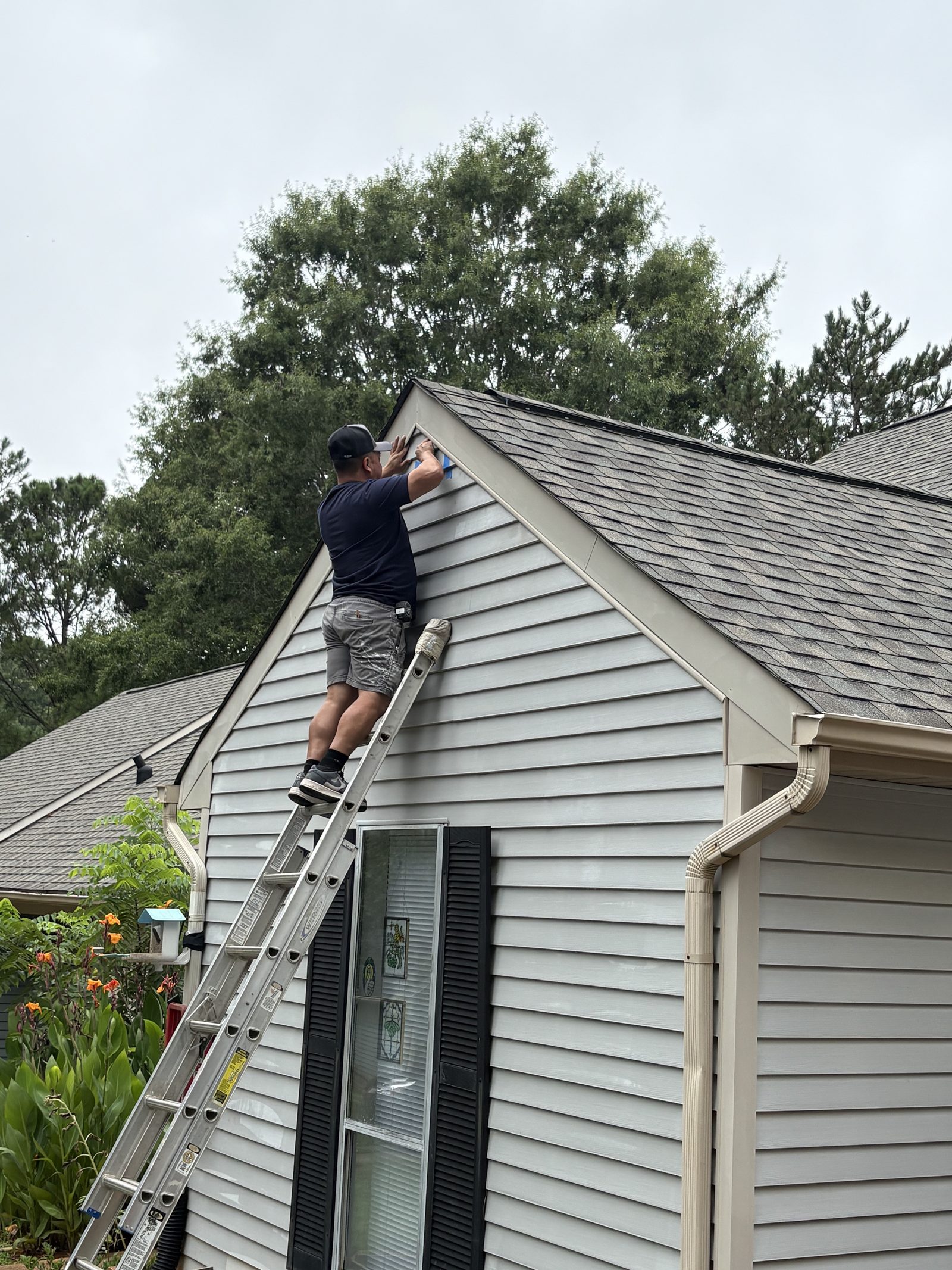 Technician completing exterior repair from a ladder